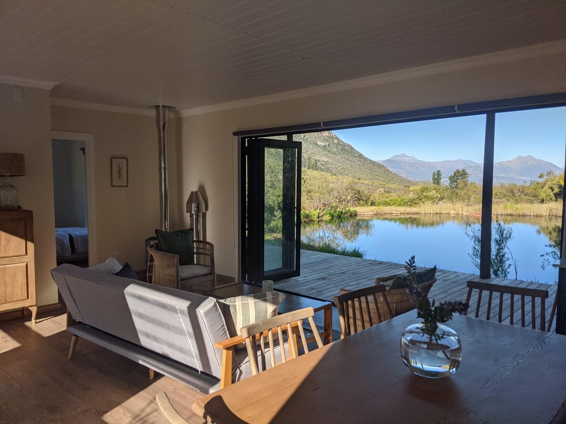 The living area at Leopard Valley Eco Retreat, opening onto a dam with mountains beyond