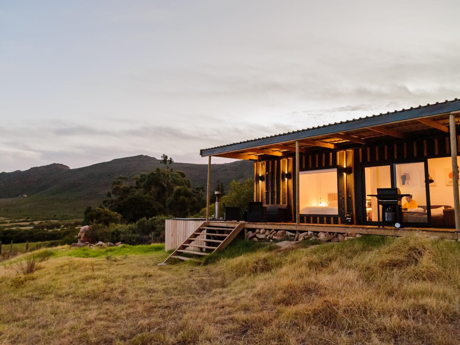 A Springsteen cabin lit up at dusk against the hills