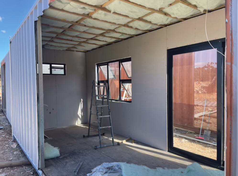 Inside a home under construction: insulation in the ceiling and boarded walls going in