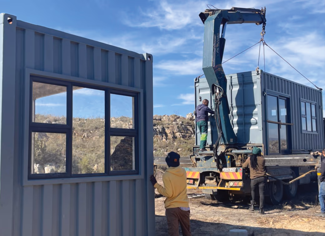 The crew guiding a container home as the crane lifts it off the truck