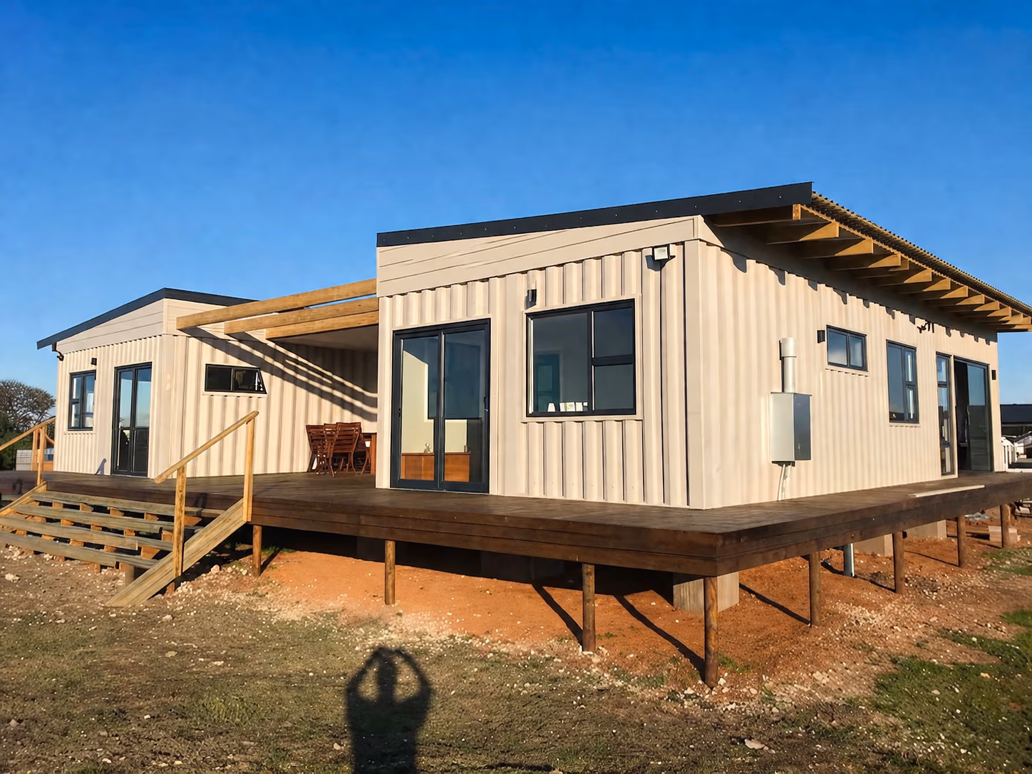 Andre's finished container home with a wooden deck and outdoor seating