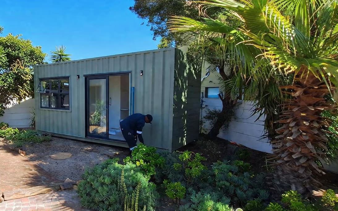 Jean's container home tucked among palm trees and garden greenery